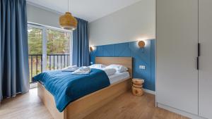 Un dormitorio con una cama con paredes azules y una ventana en Apartamenty Sun & Snow Zapach Lasu - Naturalne SPA, en Karwica