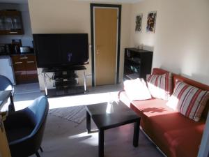 a living room with a red couch and a flat screen tv at Ferienbungalow Am Birkenwäldchen in Kolonie Röntgental