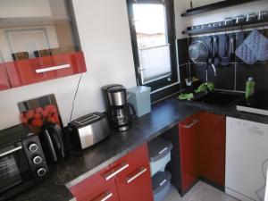 a small kitchen with red cabinets and a black counter top at Ferienbungalow Am Birkenwäldchen in Kolonie Röntgental
