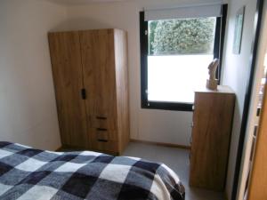 a bedroom with a bed and a window and a cabinet at Ferienbungalow Am Birkenwäldchen in Kolonie Röntgental