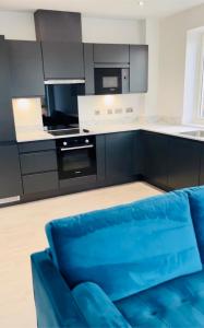 2 Bedroom Apartment In Kew Bridge في Kew Bridge: غرفة معيشة مع أريكة زرقاء في مطبخ