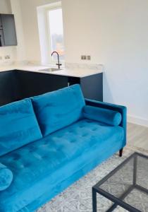 2 Bedroom Apartment In Kew Bridge في Kew Bridge: أريكة زرقاء في غرفة المعيشة مع مطبخ