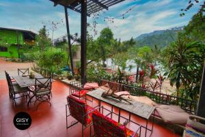 a patio with tables and chairs and a view of a mountain at GISY Lake House in Sóc Sơn