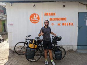 a man giving a thumbs up next to two bikes at Awaara Backpackers Hostel, Alibag in Alibag