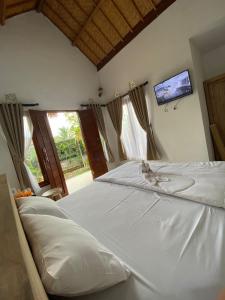 1 cama blanca grande en un dormitorio con TV en Candy home stay en Klungkung