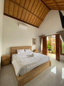 1 dormitorio con 1 cama grande con sábanas blancas en Candy home stay en Klungkung