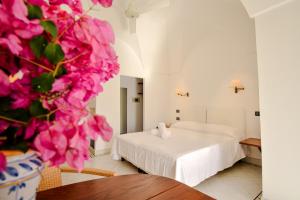 - une chambre avec un lit et un vase de fleurs roses dans l'établissement Mursia Wellness Hotel, à Pantelleria
