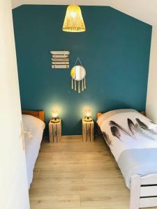 a bedroom with two beds and a blue wall at Le franc 1949 in Toussaint