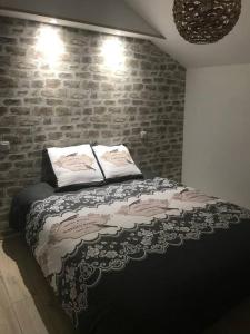 a bed in a room with a brick wall at Le franc 1949 in Toussaint +12 photos