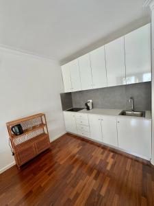 a kitchen with white cabinets and a wooden floor at Altamira Studio in Viana do Castelo