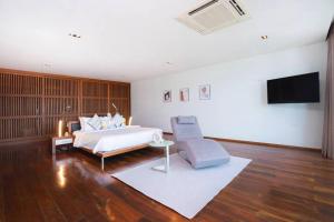 a bedroom with a bed and a tv and a chair at EVA Beach sea view Four room villa in Ban Saiyuan (1)