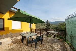 a table and chairs with a green umbrella on a patio at Lovely house in Santa Luria