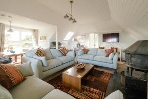 Una sala de estar con dos sofás y una mesa. en Fishermans Loft - A seaside house in Thorpeness with direct access to the beach - Aldeburgh Coastal Cottages, en Thorpeness
