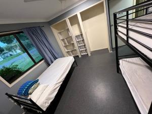 a bedroom with two bunk beds and a window at Tomato Backpackers in Bundaberg