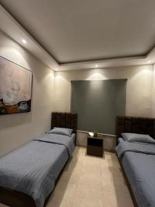 1 dormitorio con 2 camas y un cuadro en la pared en هابي رومز en Al Khobar