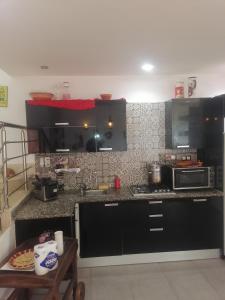 a kitchen with black cabinets and a microwave and a table at Villa de luxe avec piscine in Korba