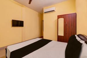 1 dormitorio con 1 cama y TV en la pared en OYO Grand Stay en Chennai