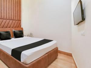 um quarto com uma cama e uma televisão na parede em OYO Hotel Blessing em Karnal