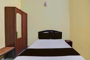 チェンナイにあるOYO Grand Stayのベッドルーム1室(ベッド1台付)、木製キャビネットが備わります。
