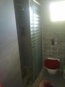 a bathroom with a shower and a toilet with a red seat at Villa de luxe avec piscine in Korba