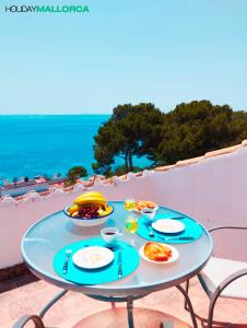 Una mesa azul con platos de comida en un balcón. en Aucanada Love Nest, en Alcudia