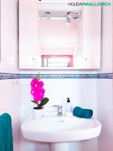 Un baño con un lavabo con una flor rosa. en Aucanada Love Nest, en Alcudia