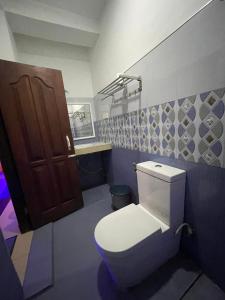 ein Bad mit einem WC und einer braunen Tür in der Unterkunft White House Adam`s Peak in Nallathanniya