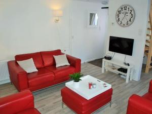 sala de estar con sofá rojo y TV en Vakantiehuis Voor Anker, en Egmond aan Zee