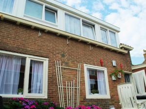 una casa de ladrillo rojo con ventanas blancas y flores en Vakantiehuis Voor Anker, en Egmond aan Zee