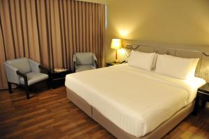 een slaapkamer met een groot wit bed en een stoel bij New Season Hotel in Hat Yai