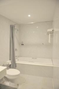 ein weißes Badezimmer mit einer Badewanne, einem WC und einem Waschbecken in der Unterkunft New Season Hotel in Hat Yai