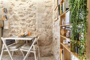 a table and chairs in a room with a stone wall at Vico Prato 1, gocce di Sicilia in Ragusa +17 photos