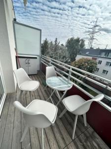 un balcone con 3 sedie e un tavolo in vetro su un edificio di Ruheoase in Wien a Vienna