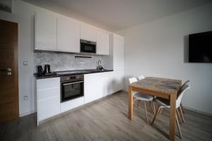 eine Küche mit weißen Schränken und einem Holztisch mit Stühlen in der Unterkunft Garni hotel Svitavy in Svitavy