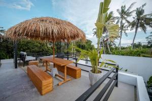 eine Terrasse mit einem Tisch, Bänken und einem Sonnenschirm in der Unterkunft 4BR Luxury Tropical Jungle Villa 4 Mins to Beach in Tanah Lot