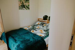 a small bedroom with a bed with a blue comforter at Rowerowe domki in Dobrenice