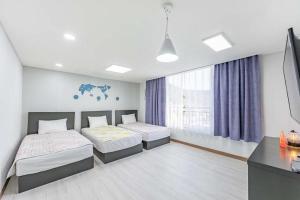 Jin Arirang Hostel في يوسو: غرفة نوم بسريرين وتلفزيون فيها