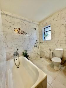 a white bathroom with a tub and a toilet at BohoLush by Evanka in Vagator