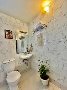 a white bathroom with a toilet and a sink at BohoLush by Evanka in Vagator
