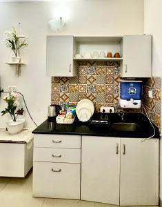 a kitchen with white cabinets and a sink at BohoLush by Evanka in Vagator
