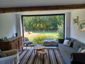 uma sala de estar com um sofá e uma grande janela em L'Etable de Joseph- calme et rivière em Honnay