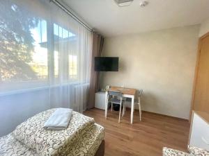 a bedroom with a bed and a table and a window at Savan House "Easy Kaunas" in Kaunas