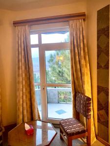Cette chambre dispose d'une fenêtre avec une chaise et une table. dans l'établissement Rock City Resort, à Swat