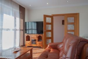 a living room with a leather couch and a television at AV Casa Aurora - Quintes in Villaviciosa