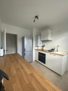 a kitchen with white cabinets and a stainless steel refrigerator at Appartement spacieux avec parking in Lempdes