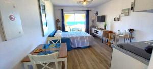 a bedroom with a bed and a kitchen with a table at Studio standing classé avec terrasse vue mer " les pieds dans l'eau " à Algajola in Algajola