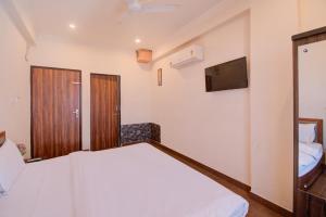 a bedroom with a white bed and a tv at Hotel Bhagwati Palace in Jaipur