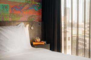 ein Bett mit einem weißen Kissen neben einem Fenster in der Unterkunft Crown Hotel Eindhoven Centre in Eindhoven