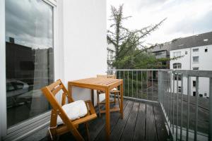 Apartments - Kitchen & More في دوسلدورف: طاولة خشبية وكرسي على شرفة