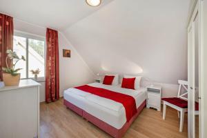 a white bedroom with a large bed with red pillows at Ferienhaus Sonne 6c in Korswandt